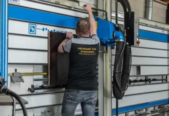 Medewerker van Veldkamp RVS die een RVS plaat positioneert in een kantbank (zetbank) voor het nauwkeurig buigen en vormen van plaatmateriaal.