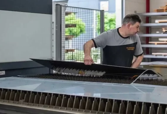 Medewerker van Veldkamp RVS die een gesneden RVS plaat uit een lasersnijmachine verwijdert en controleert op kwaliteit en nauwkeurigheid.