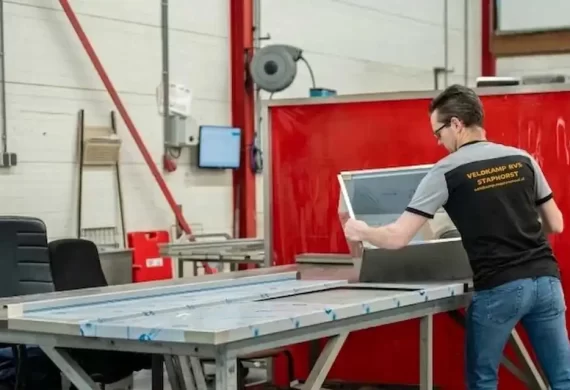 Medewerker van Veldkamp RVS die een RVS behuizing of constructie controleert en positioneert op een werktafel in de werkplaats, ter voorbereiding op montage of verdere afwerking.