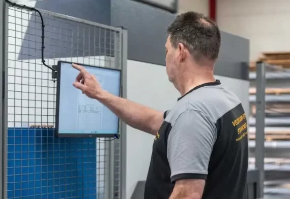 Medewerker van Veldkamp RVS die een digitale technische tekening bekijkt en bedient via een scherm bij een machine, voor het instellen of controleren van een productieproces.