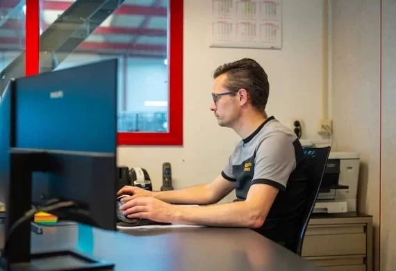 Medewerker van Veldkamp RVS die achter een bureau op een computer werkt in een kantooromgeving, zichtbaar geconcentreerd bezig met administratieve of technische werkzaamheden.