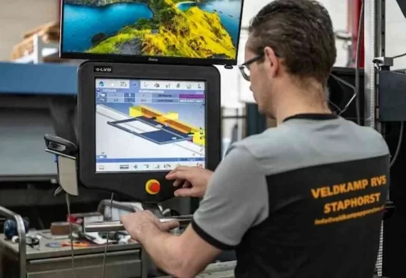 Medewerker van Veldkamp RVS in Staphorst die een CNC-machine bedient en een technische tekening op het scherm instelt voor het bewerken van een RVS onderdeel.